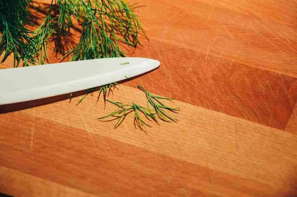 Dill leaves and a knife on the cutting board